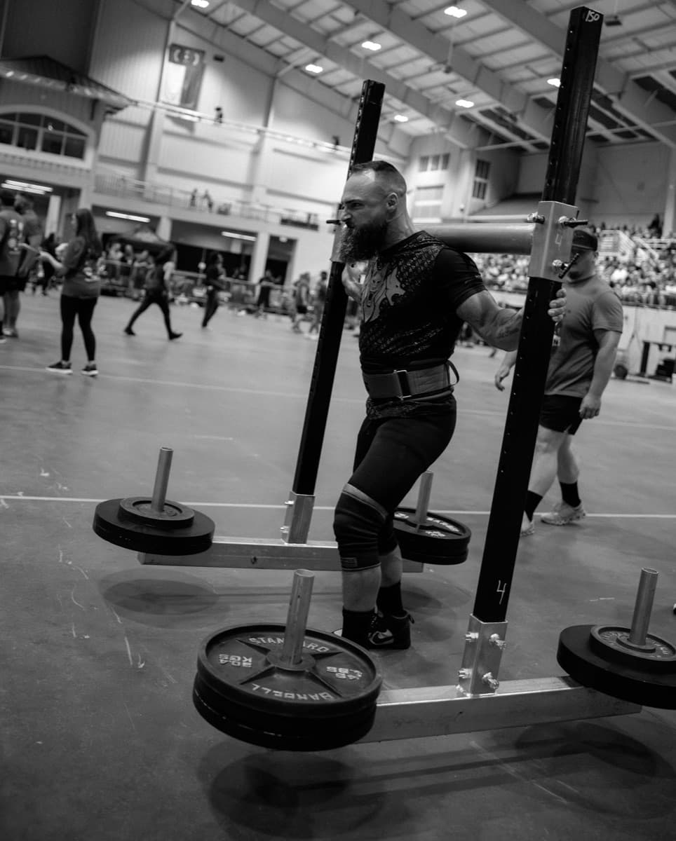 Yoke walk in progress, mid-stride, at a strongman contest.