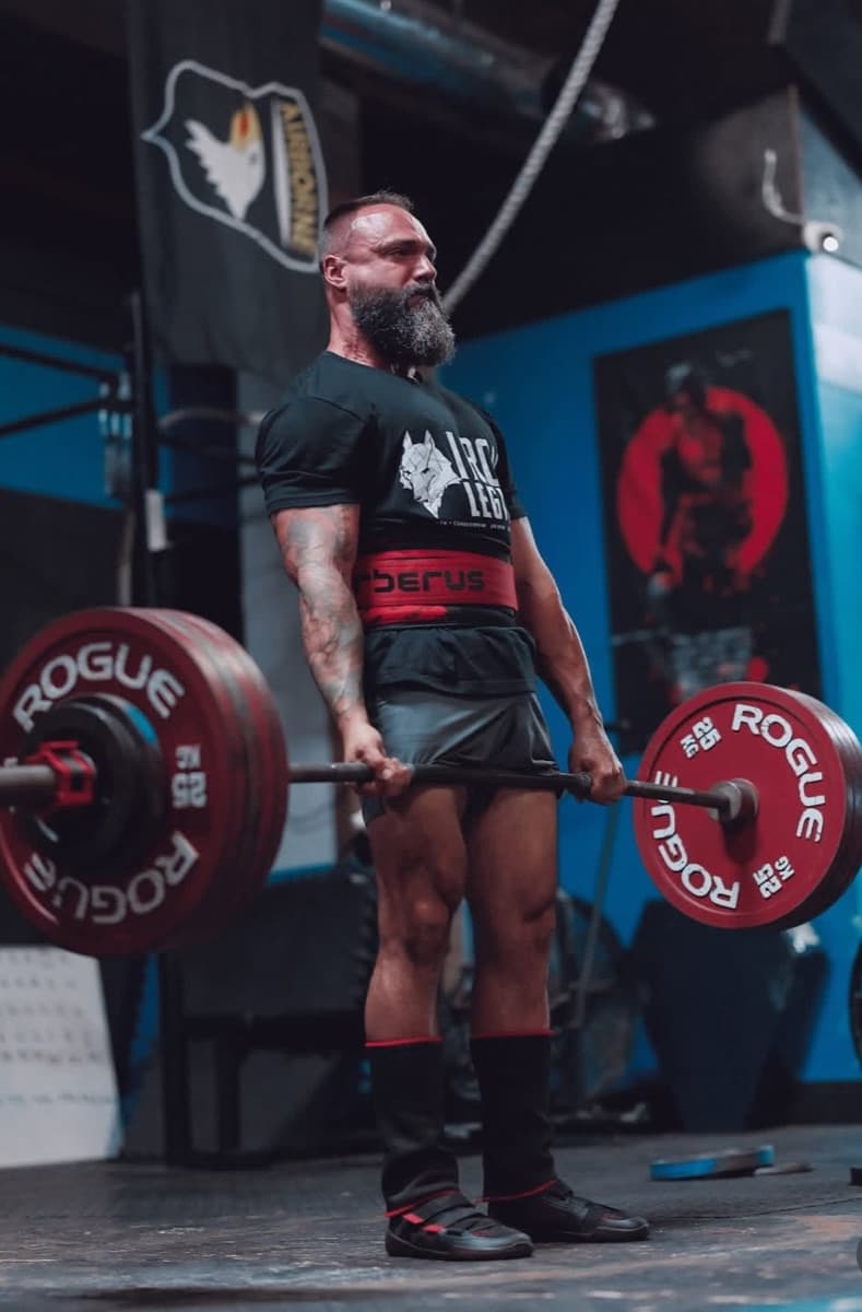 Deadlift lockout with red bumper plates at Iron Legion.